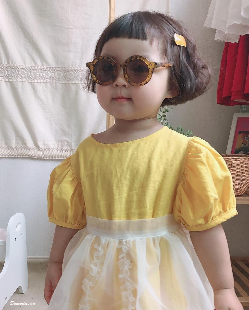 Em bé mặc váy vàng đeo kính râm cực ngầu