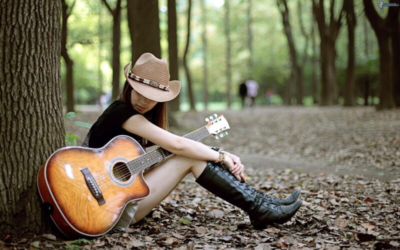 Ảnh cô gái cô đơn chụp bên cây đàn guitar