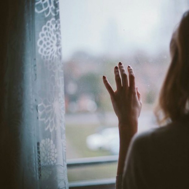 Bàn tay bất lực đặt lên kính cửa sổ thể hiện sự nuối tiếc và thất vọng