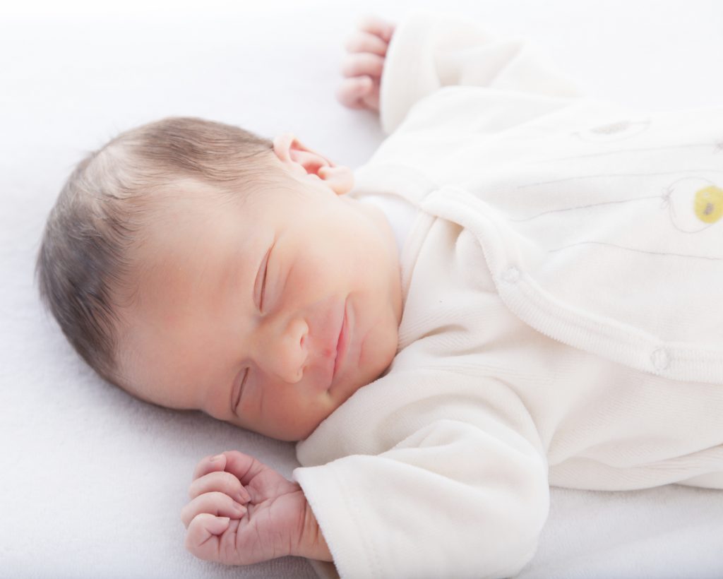 Hình em bé mới sinh buồn ngủ hài hước ngủ ngon lành với nụ cười trên môi