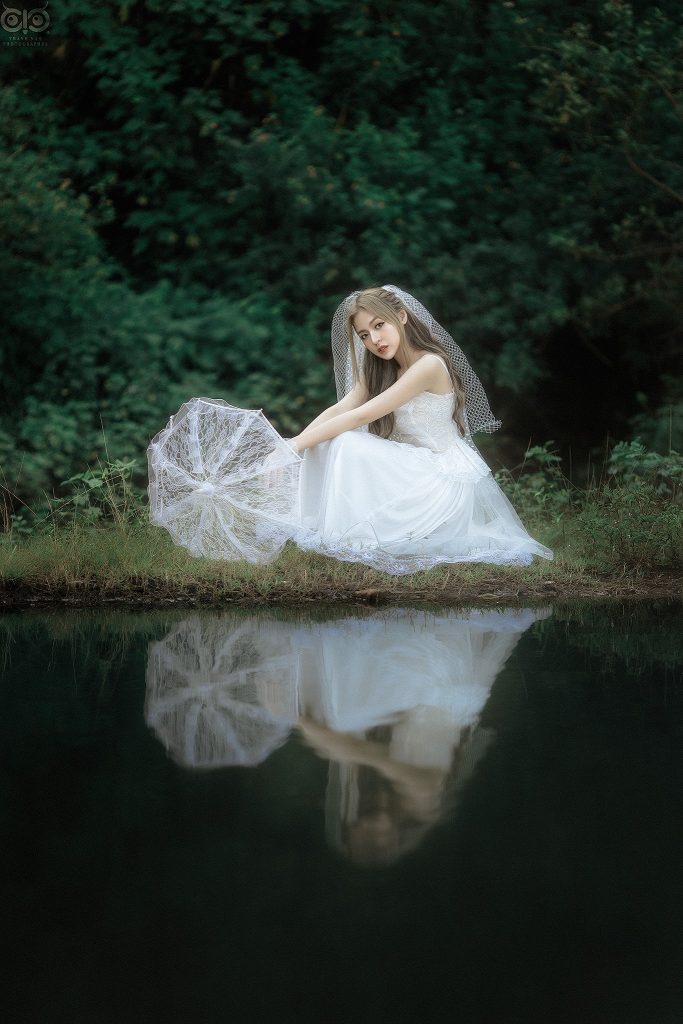 Cô dâu xinh đẹp mặc bộ váy cưới đơn giản ngồi bên hồ