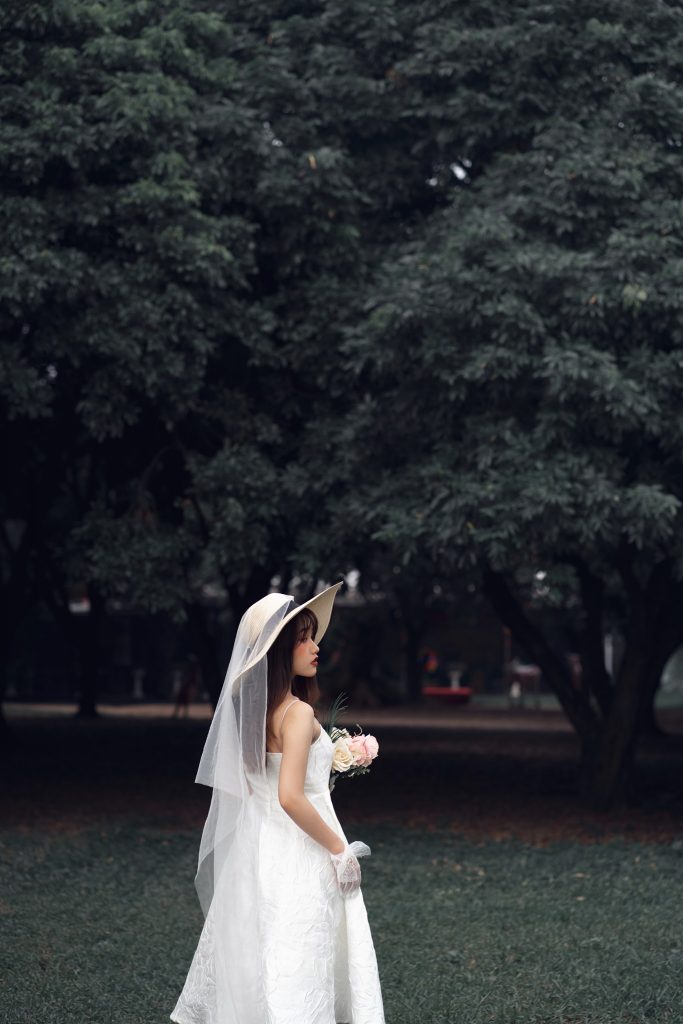 Ảnh chụp sau lưng cô dâu đơn với tông màu ma mị background là những cái cây cực to