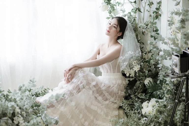 Ảnh chụp cô dâu xinh đẹp đang ngồi giữa những bông hoa trắng bên cừa sổ
