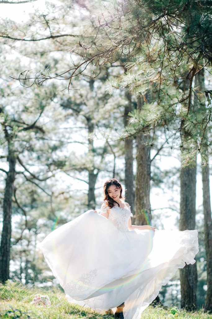 Khoảnh khắc cô dâu đang quay chiếc váy cưới của mình bên dưới ánh năng xuyên qua lá cây đẹp như trong truyện cổ tích