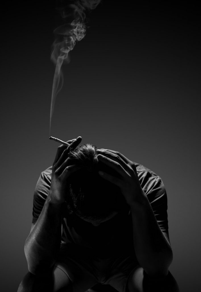Hình trắng đen chàng trai ôm đầu thất vọng trên tay cầm điếu thuốc