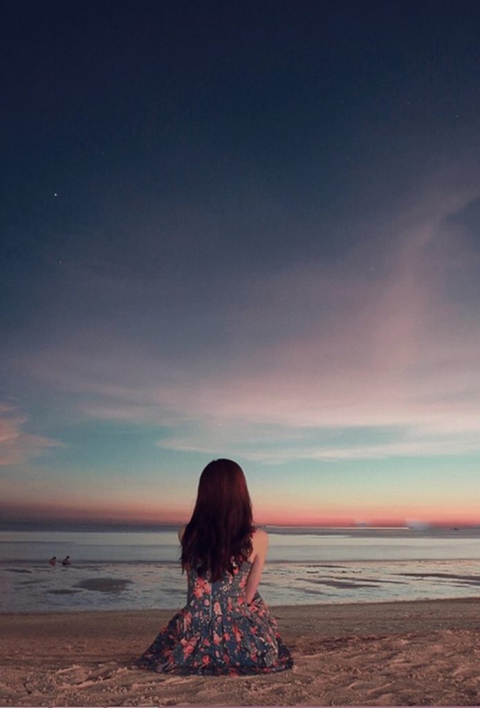 Cô gái buồn chán cô đơn ngồi trên bờ biển ngắm bầu trời