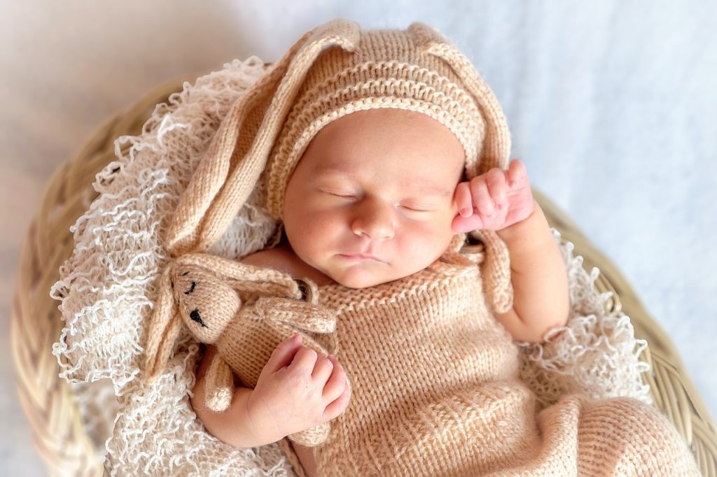 Em bé ôm gáu bông đeo mũ tai thỏ ngủ rất đáng yêu