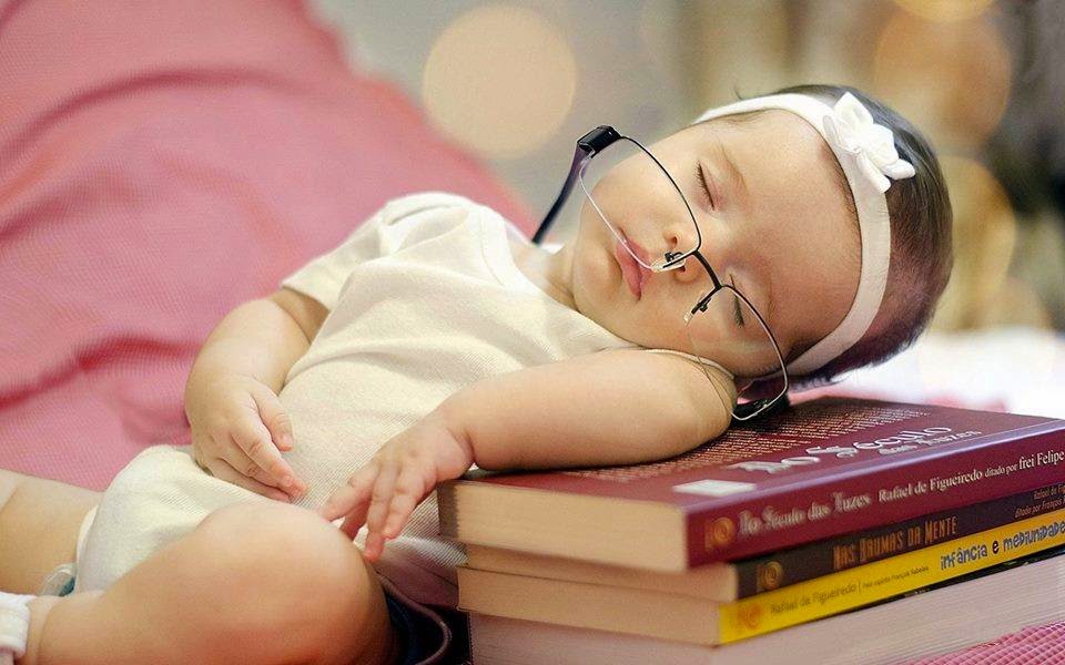 Em bé đeo kính ngủ gục trên đống sách cực đáng yêu