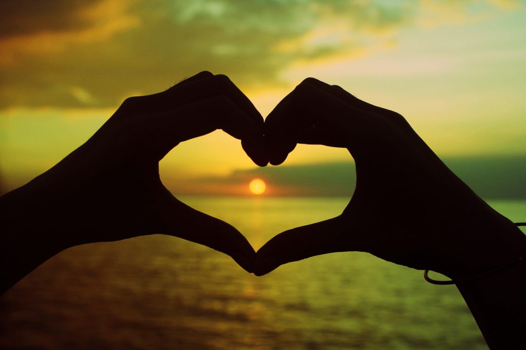 Hình ảnh hai bàn tay chụm lại thành hình trái tim ở giữa là mặt trời