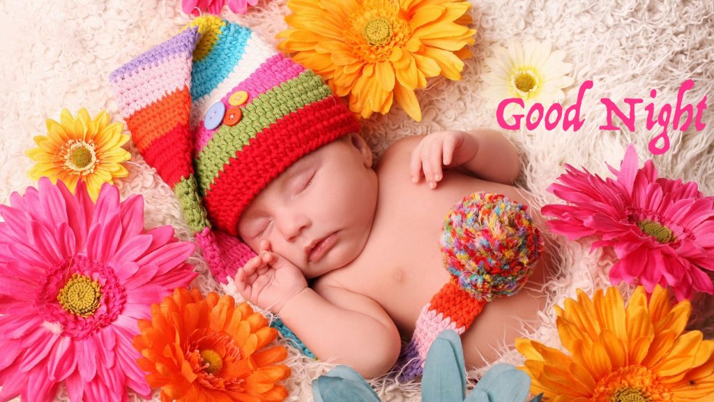 Em bé ngủ giữa những bông hoa màu và đội chiếc mũ càu vồng thật đáng yêu
